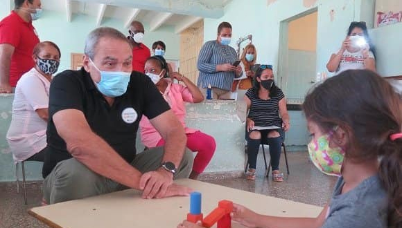 Vicente Vérez conversa con una niña durante el proceso de vacunación pediátrica. Foto: Tomada del muro de Facebook de la autora.