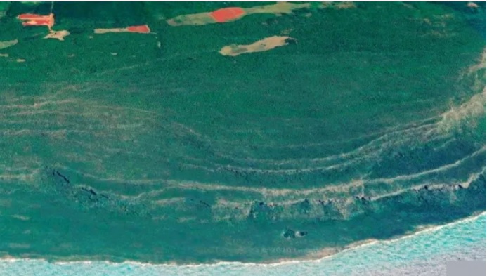   Fig. 2. Terrazas emergidas al SE de Cabo Cruz, donde se observan las bocas de cavernas en las paredes de las terrazas, solapas derrumbadas y el Hoyo Morlote.