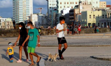 Personas con tapabocas caminan por el malecón en La Habana. Foto: Ernesto Mastrascusa / EFE